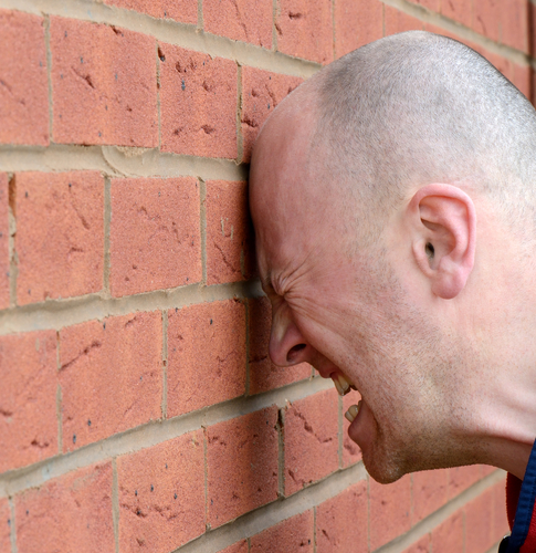 Man banging head against wall